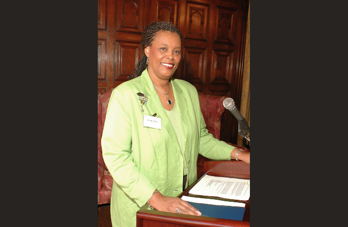 An African American woman wearing a bright green suit stands at a podium