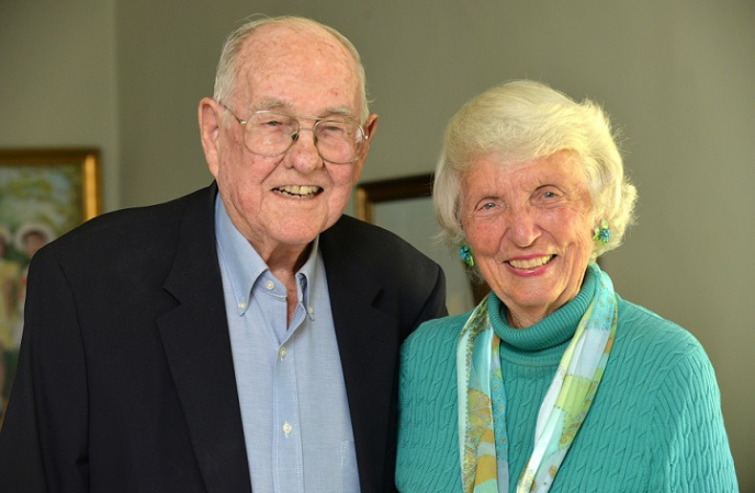 An older white couple pose inside a home