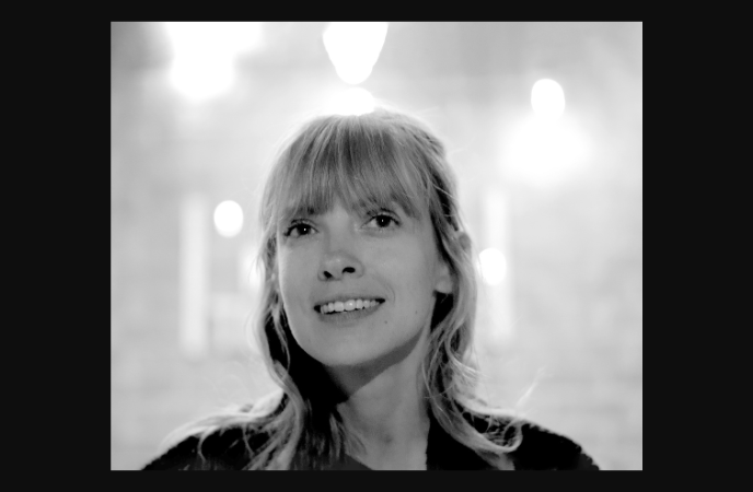 A black and white photo of a young blonde woman gazing upwards