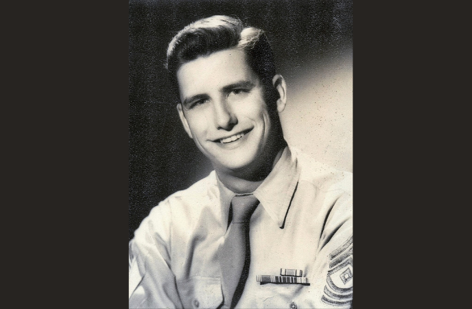 A vintage black and white portrait shows a young man in a military outfit