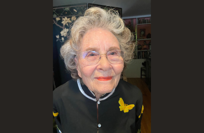 A close up head shot of an elderly woman with gray curly short hair