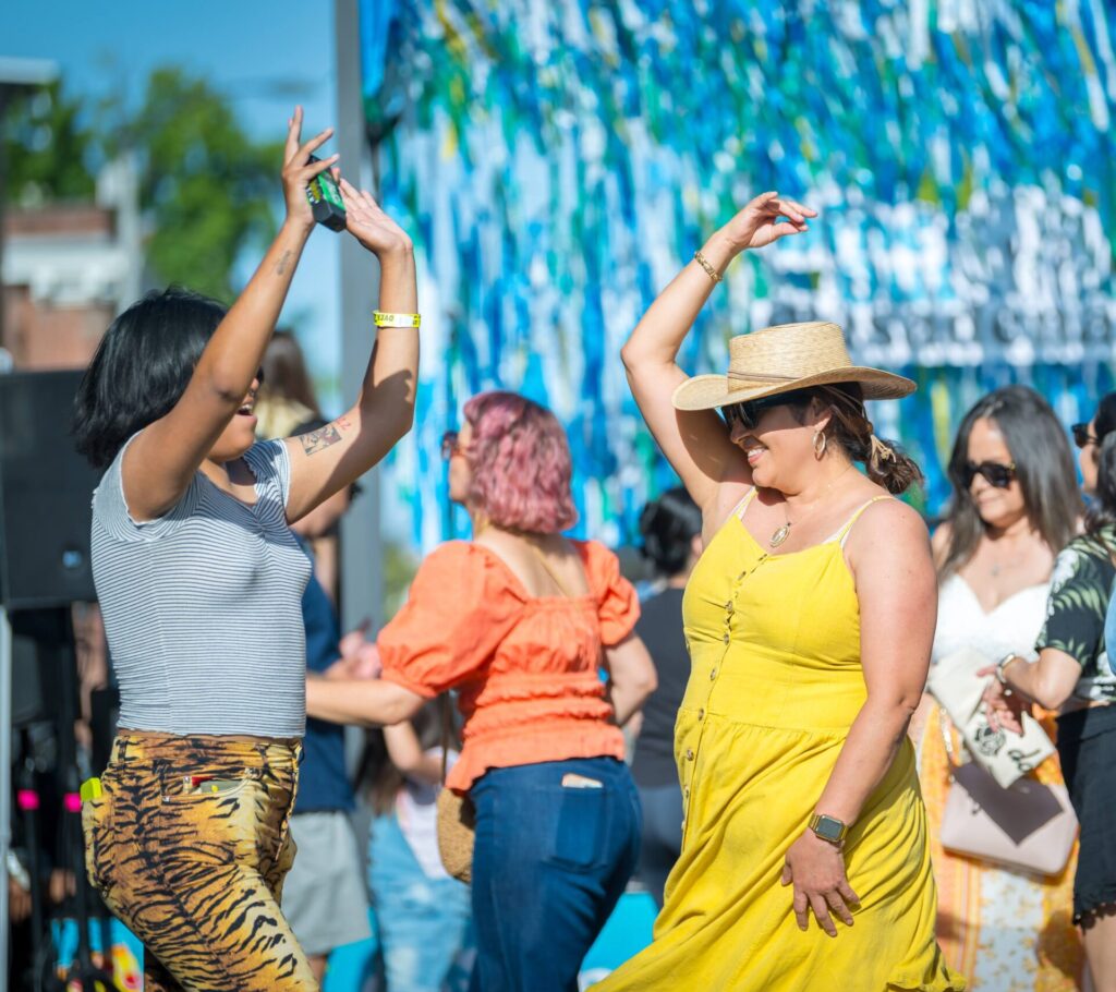 People dancing on the street with woman in a yellow dress as a focal point