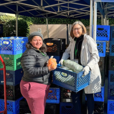 Two women unload crates of food