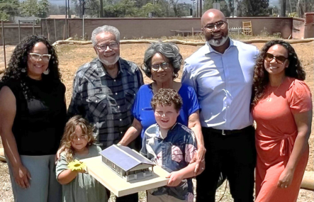 Three generations of an African American family stand on a cleared lot in Altadena following the Eaton Fire
