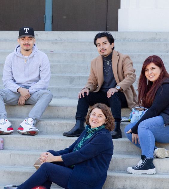 Four adults sit on an outdoor stairway