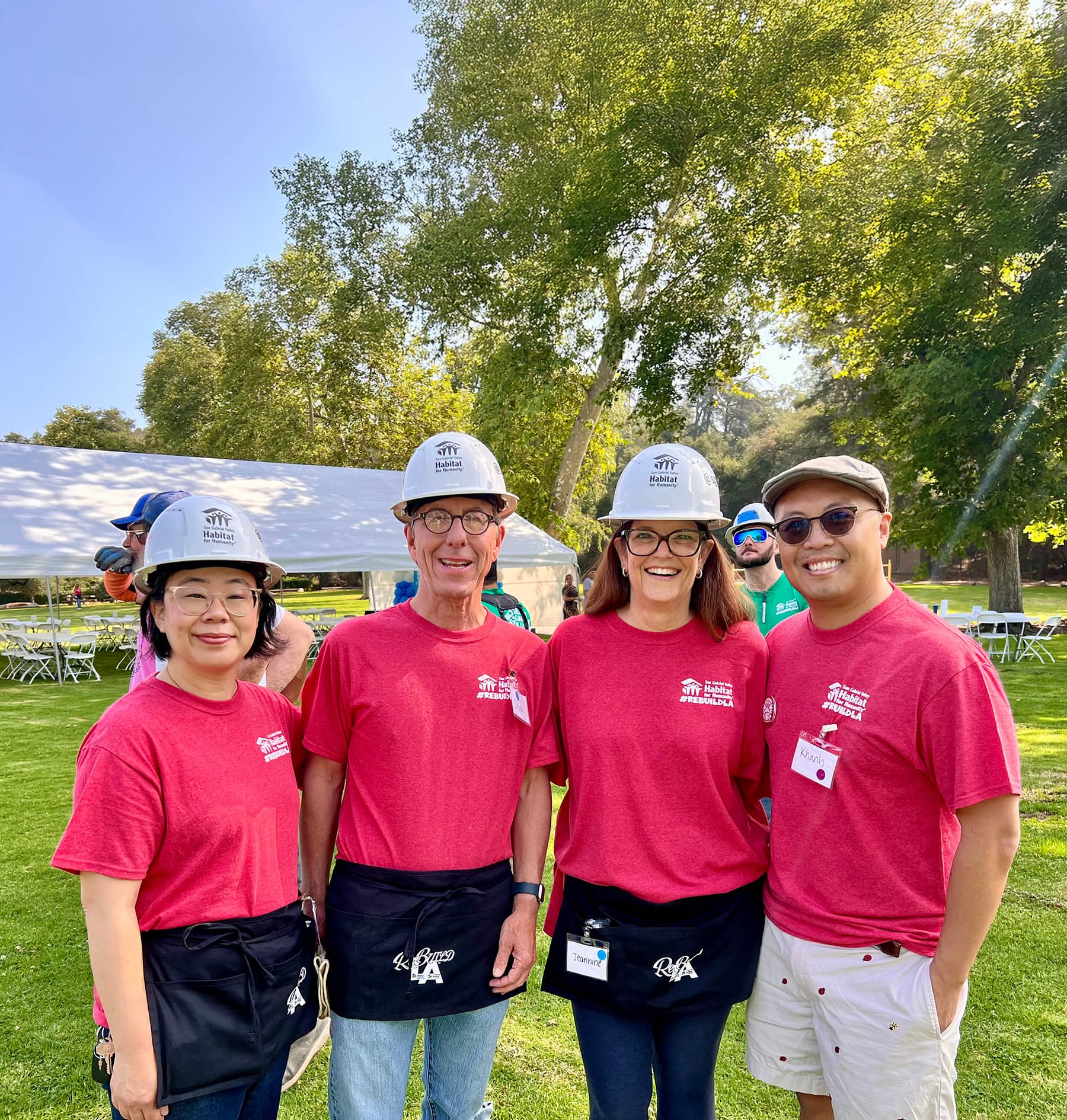 Four habitat for humanity volunteers wearing hardhats and posing for photo