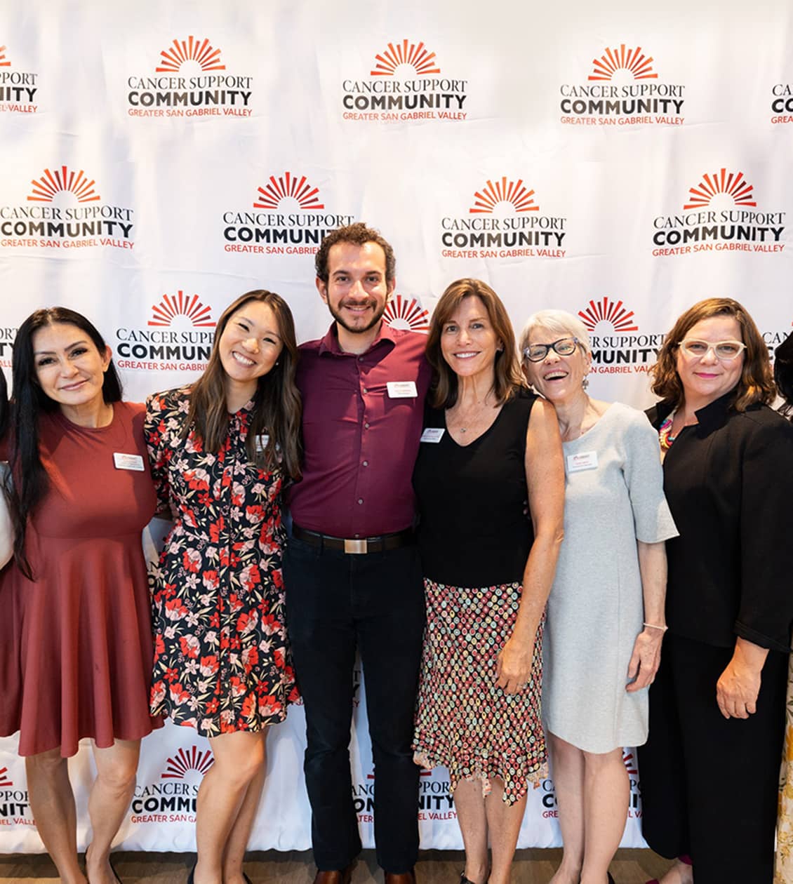 Group of people smiling for a photo in front of a logo photo wall