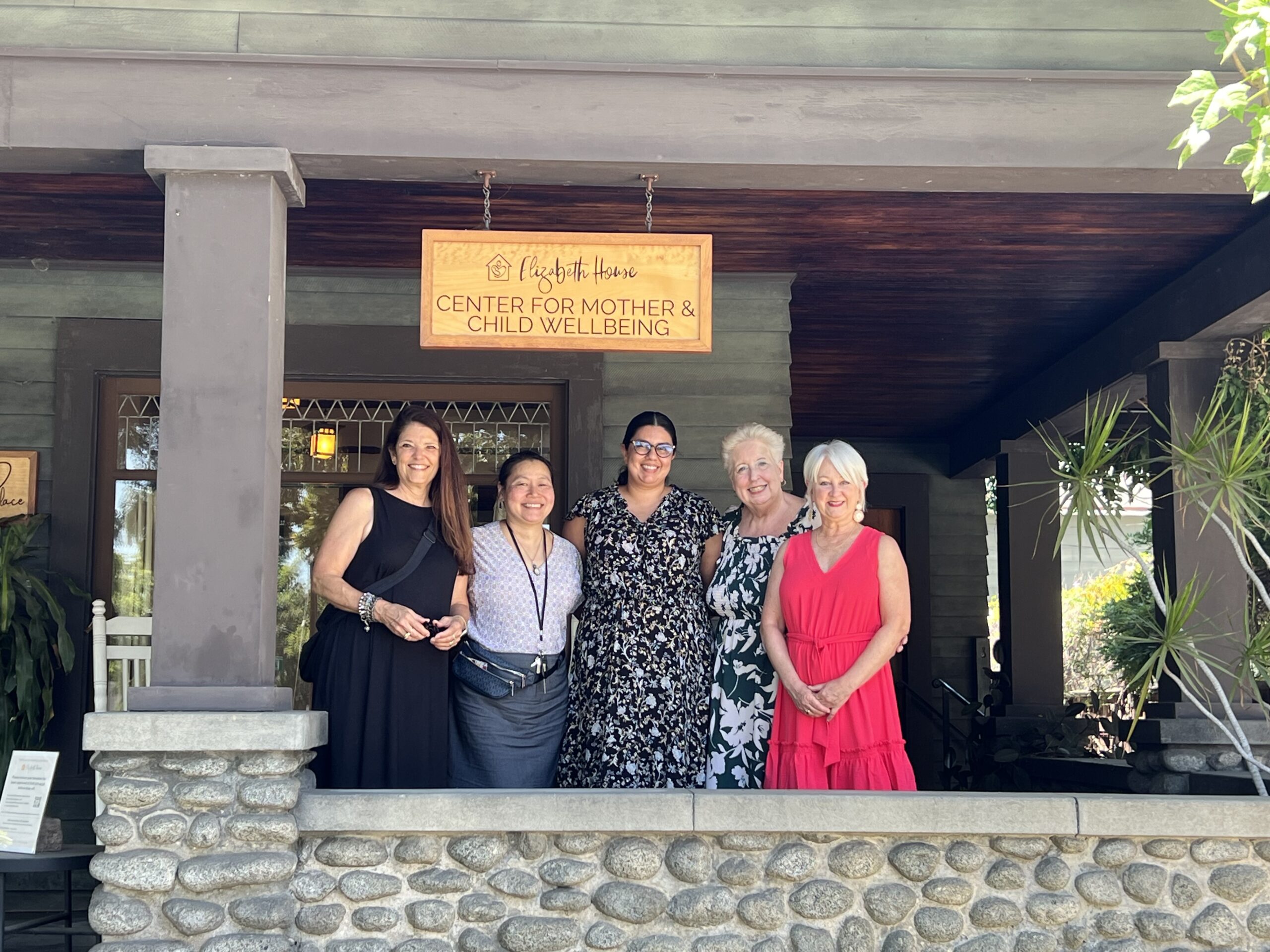 Five women standing on a porch in front of a house.