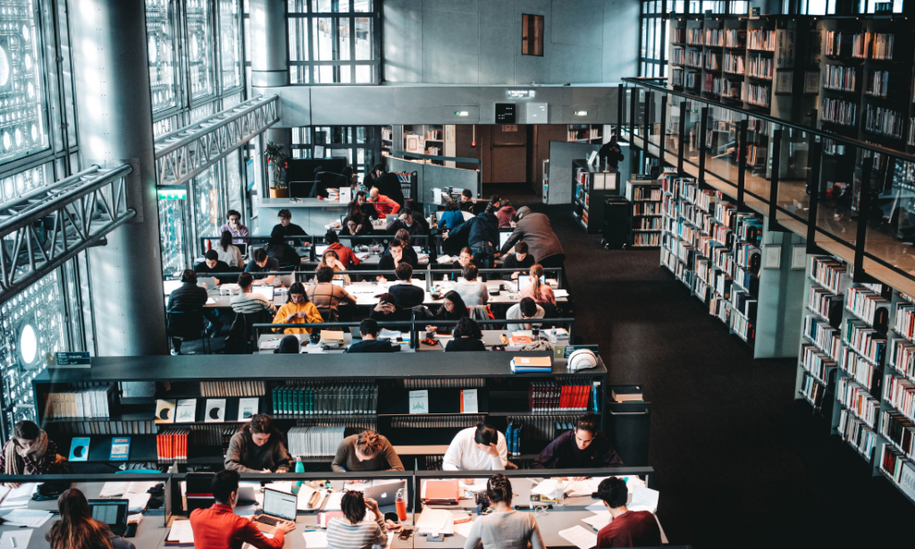 A college library is shown from above, with students visibly working and studying