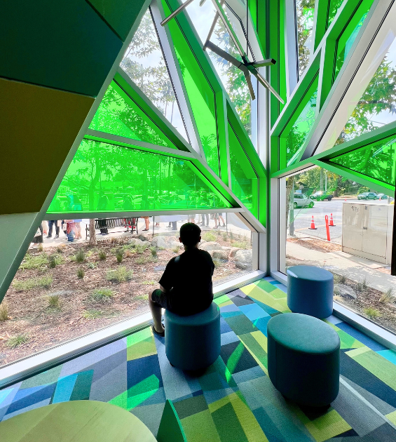 A boy is silhouetted in front of a bright green stained glass window