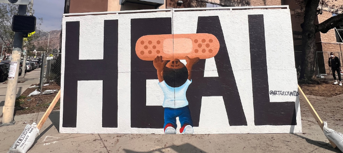 An oversized sign reads HEAL and has a young boy lifting up an Bandaid.