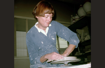 A vintage photo shows a young woman throwing a platter on a pottery wheel
