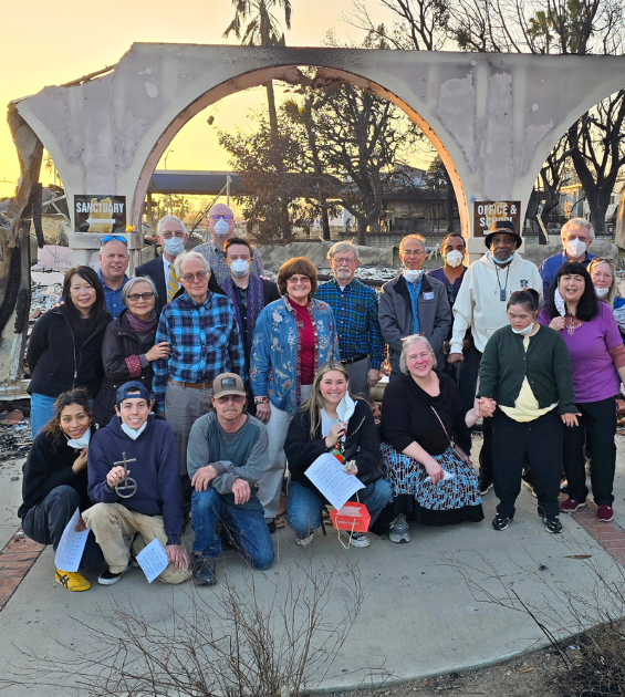 A group of adults stand before a burned out arch of a church in altadena CA