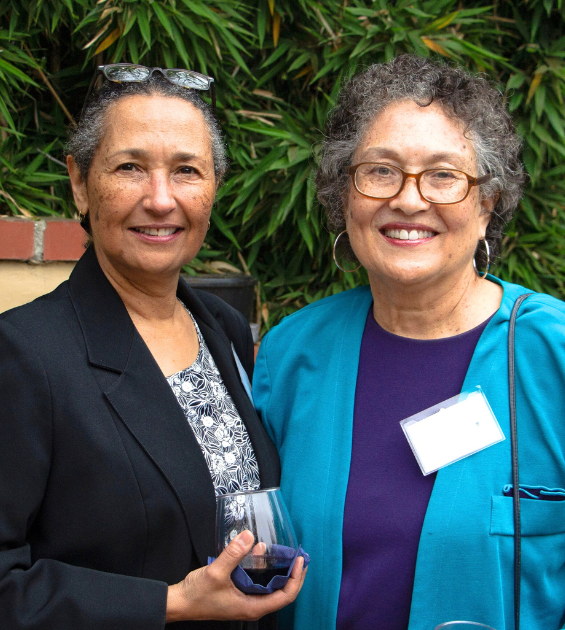 Two older women stand together posing for the camera