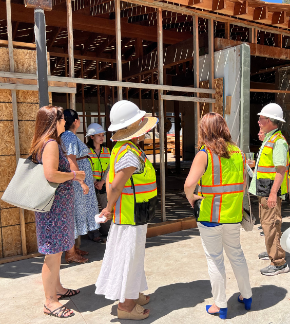 A group of people wearing bright yellow safety vests observe a construction site