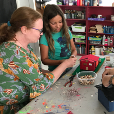 A woman helps a young girl with an art project