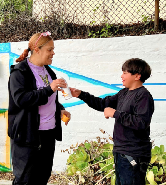 A woman holds a can of spray paint and a young boy reaches out to get it from her