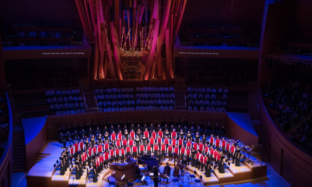 A children's chorus pictured in dark lighting with red and purple accent lights