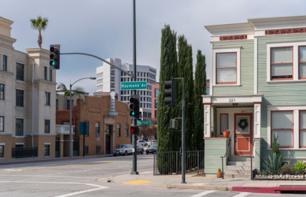 A city street corner showing various buildings of varying heights. Street sign says Raymond Ave