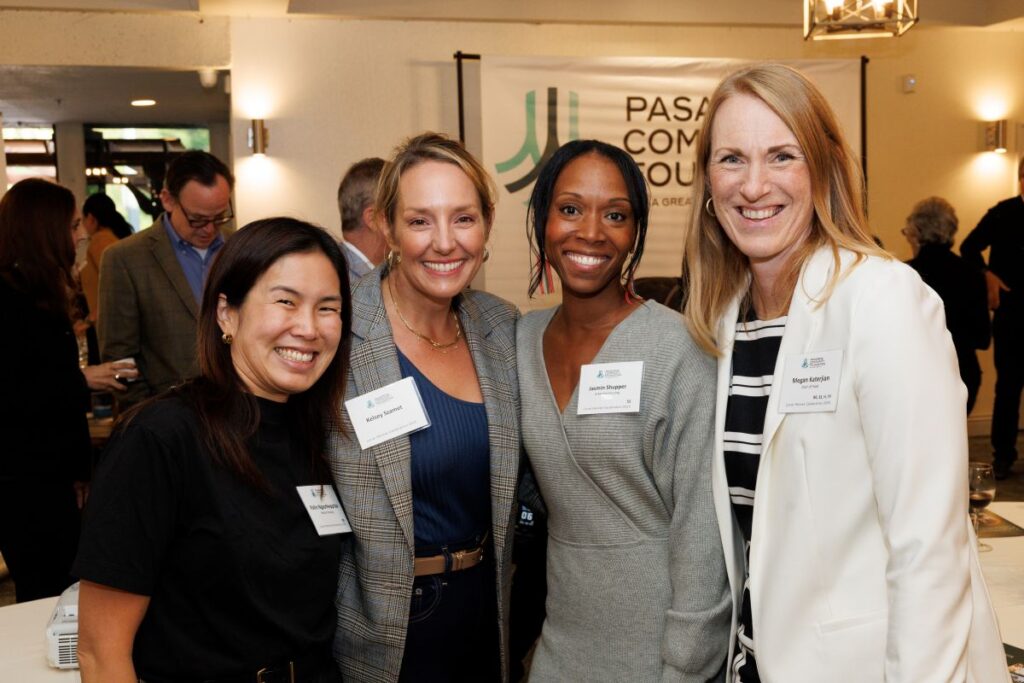Four women stand closely together, all wearing name tags