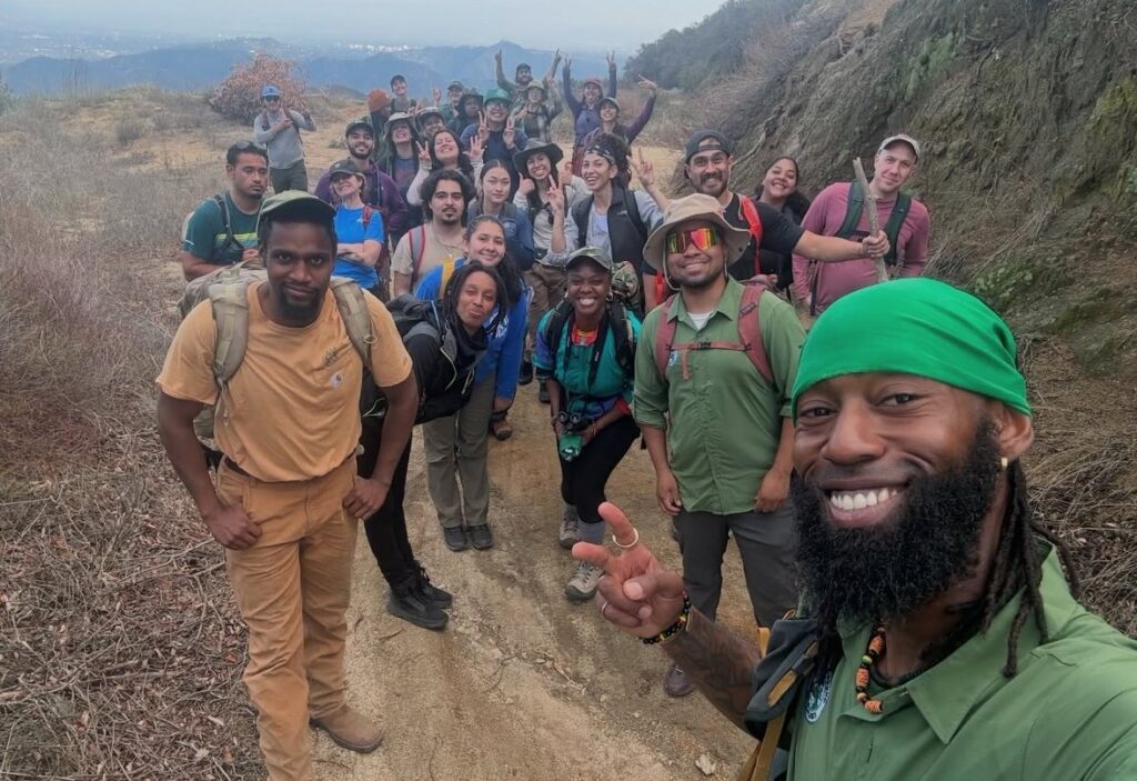 A large group of people in outdoor gear on a hiking trail
