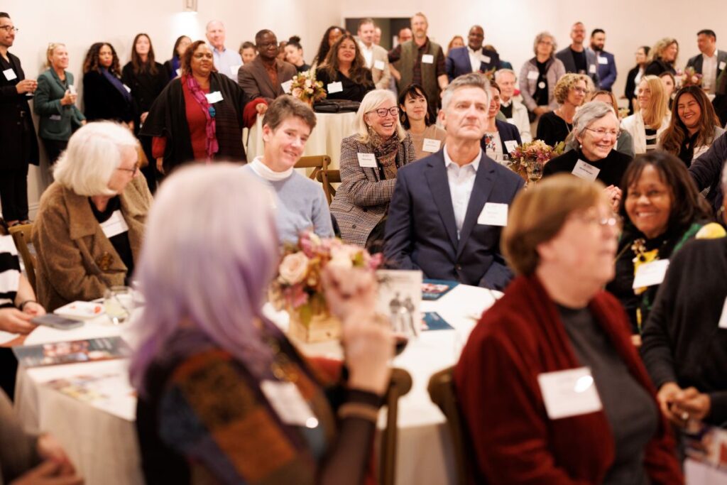 A large crowd sits at an indoor event