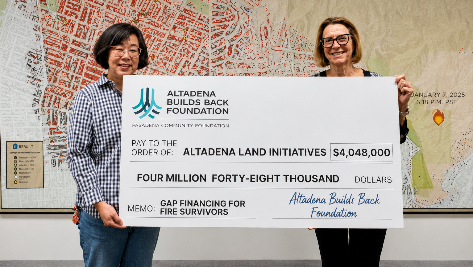 Two women standing infront of a map of the burn area in Altadena. Holding a large check.